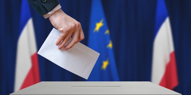 Election in France. Voter holds envelope in hand above vote ballot. French and European Union flags in background.