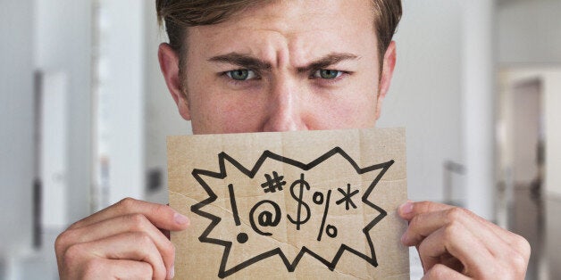 Man holding swear word sign in front of his mouth