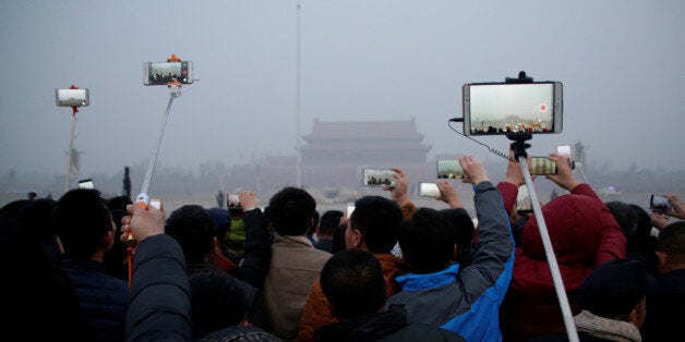 People take videos of a flag-raising ceremony during smog at Tiananmen Square after a red alert was issued for heavy air pollution in Beijing, China, December 20, 2016. REUTERS/Jason Lee