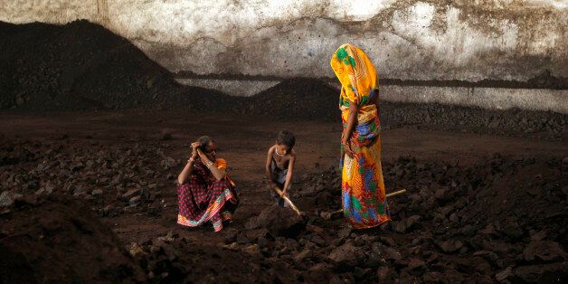 Labourers rest as a boy playfully shovels coal at a yard in the western Indian city of Ahmedabad November 20, 2014. India will allow locally registered foreign firms to mine and sell coal when commercial mining is permitted as part of the opening up of the nationalised industry after four decades, Coal Secretary Anil Swarup told Reuters. To match Interview INDIA-COAL/ REUTERS/Amit Dave (INDIA - Tags: BUSINESS POLITICS ENERGY SOCIETY EMPLOYMENT TPX IMAGES OF THE DAY)