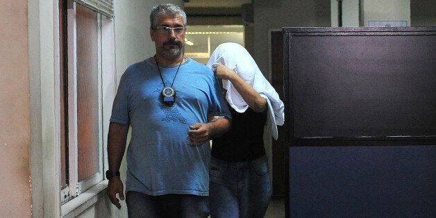 A Brazilian civil policeman escorts the wife of Greece's ambassador to Brazil Kyriakos Amiridis, Francoise de Souza Oliveira, who murdered him in a plot hatched with her police officer lover, who confessed to the crime, on December 30, 2016 in Rio de Janeiro. Amiridis, 59, was killed on December 26 by the officer, Sergio Gomez Moreira, and his charred body was found on December 29 in his burned-out rental car, a day after his wife declared him missing. / AFP / Fabio Teixeira (Photo credit should read FABIO TEIXEIRA/AFP/Getty Images)