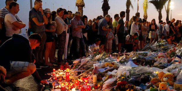 People gather around flowers and burning candles to pay tribute to victims of the truck attack along the Promenade des Anglais on Bastille Day that killed scores and injured as many in Nice, France, July 17, 2016. REUTERS/Pascal Rossignol