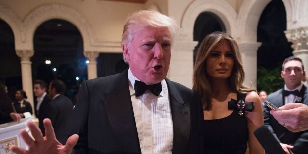 US President-elect Donald Trump answers questions from reporters accompanied by wife Melania for a New Year's Eve party December 31, 2016 at Mar-a-Lago in Palm Beach, Florida. / AFP / DON EMMERT (Photo credit should read DON EMMERT/AFP/Getty Images)