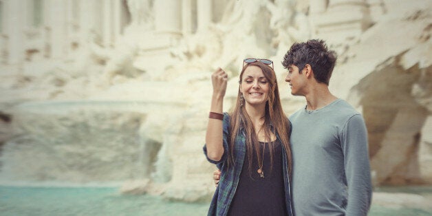 Tourist couple tossing a coin in the Trevi fountain