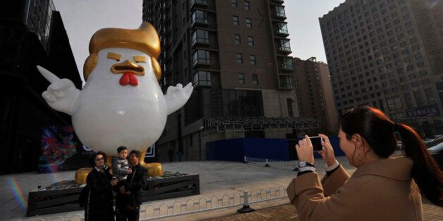TAIYUAN, CHINA - DECEMBER 24: People pose in front of the rooster sculpture with the classical gestures of American president-elect Donald Trump at the N1 square of Fashionwalk shopping mall on December 24, 2016 in Taiyuan, Shanxi Province of China. A shopping mall set up a rooster sculpture to welcome the Year of Rooster. (Photo by VCG/VCG via Getty Images)
