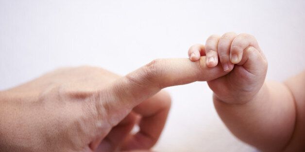 baby's small hand holding father's finger
