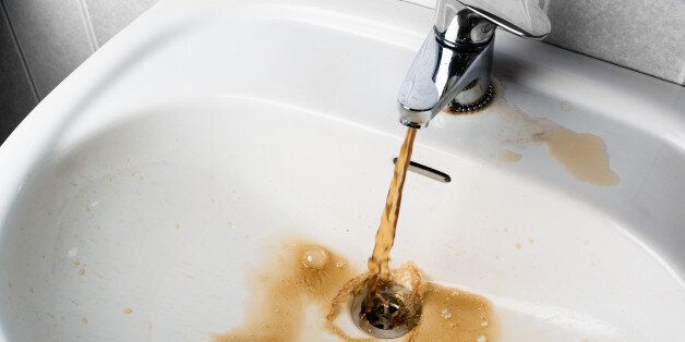 Dirty brown water running into a white sink. Looks very unhealthy,