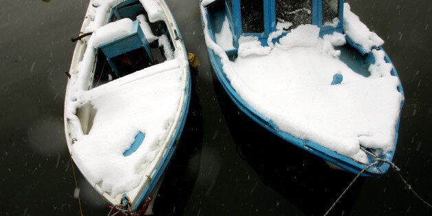 Snow-covered fishing boats are docked at a marine in Chalkida town in Evia island, northeast of Athens, January 25, 2006. More than 400 villages and towns were cut off after 36 hours of continuous snowfall while hundreds of snow-clearing vehicles struggled to keep main routes open. Ports across Greece stayed shut as icy gale-force winds swept across the Aegean sea, dropping a carpet of snow over the islands. REUTERS/Yiorgos Karahalis