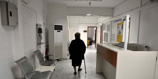 A woman walks a closed branch Greek state health fund EOPYY in an Athens suburb on February 17, 2014, as doctors and other staff refuse to hand over control of the organizations polyclinics despite the demands of the Health Ministry. Doctors at the state health fund EOPYY have been on strike since November, protesting against a planned restructuring of the loss-making organisation. The ministry insists the polyclinics will reopen in 30 days with a new system. AFP PHOTO/ LOUISA GOULIAMAKI (Photo credit should read LOUISA GOULIAMAKI/AFP/Getty Images)