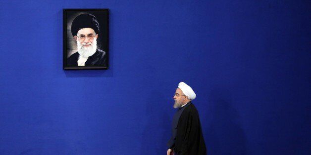 Iranian President Hassan Rouhani walks past a portrait of Iranian supreme leader Ayatollah Ali Khamenei as he arrives to give a speech during a press conference in the capital Tehran on August 29, 2015. AFP PHOTO / ATTA KENARE (Photo credit should read ATTA KENARE/AFP/Getty Images)
