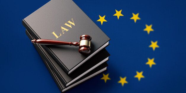 Wooden gavel and a leather covered law books on EU flag. The book and the gavel are lit by a spotlight from the upper left corner and casting soft shadows on background. Nicely textured.