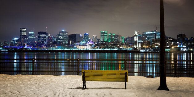 A winter night in Montreal. Park bench and street light with the St Lawrence river and downtown Montreal in the background.