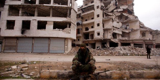 A member of forces loyal to Syria's President Bashar al-Assad sits near damaged buildings in Aleppo's Salaheddine district, Syria December 16, 2016. REUTERS/Omar Sanadiki