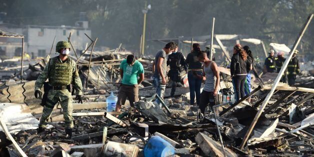 Soldiers and local residents search amid the debris left by a huge blast that occured in a fireworks market in Mexico City, on December 20, 2016 killing at least 26 people and injuring scores.The conflagration, in the suburb of Tultepec, set off a quickfire series of multicolored blasts and a vast amount of smoke that hung over Mexico City. / AFP / RONALDO SCHEMIDT (Photo credit should read RONALDO SCHEMIDT/AFP/Getty Images)