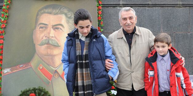 The grandson of Joseph Stalin (Dzhugashvili), Yevgeny Dzhugashvili (C) poses with his grandsons Josef Vissarionovitch Dzhugashvili (L) and Vaso Dzhugashvili (R) next to the portrait of their famous relative in the central square of Gori, some 80 kilometers from Tbilisi on December 21, 2009. People pay tribute to Joseph Stalin 130 years after his birth, with debate still raging in the country over the reputation of a leader seen in the West as an evil tyrant. While historians blame Stalin for the deaths of millions in purges, prison camps and forced collectivization, many in Russia still praise him for leading the Soviet Union to victory over Nazi Germany in World War II. AFP PHOTO/ VANO SHLAMOV (Photo credit should read VANO SHLAMOV/AFP/Getty Images)