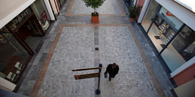 Pedestrians pass luxury goods stores in an empty arcade at the McArthurGlen designer shopping outlet in the Spata district of Athens, Greece, on Tuesday, Jan. 10, 2012. Greece is in final negotiations to persuade investors to forgive at least half of its debt, the euro area's first large-scale restructuring, as Greeks are told to gird for more austerity if they want to keep the euro. Photographer: Kostas Tsironis/Bloomberg via Getty Images