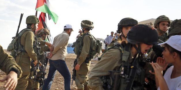 Israelis soldiers detain a Palestinian activist during a demonstration against the construction of Jewish settlements in the village of Ein al-Beida, north of the city of Nablus in the West Bank, on November 17, 2016. / AFP / ABBAS MOMANI (Photo credit should read ABBAS MOMANI/AFP/Getty Images)