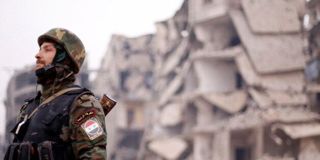 A member of forces loyal to Syria's President Bashar al-Assad stands near damaged buildings in Aleppo's Salaheddine district, Syria December 16, 2016. REUTERS/Omar Sanadiki