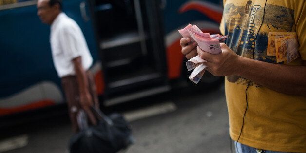 A transportation employee counts money at a bus stop in Caracas, Venezuela, on Wednesday, Dec. 14, 2016. Roughly 24 hours ahead of a planned rollout of much awaited -- and much needed -- larger-denomination bolivar bills in Venezuela, banks had yet to receive the new tender on Wednesday, nor was it clear whether the banknotes had even arrived in the country. Photographer: Wil Riera/Bloomberg via Getty Images