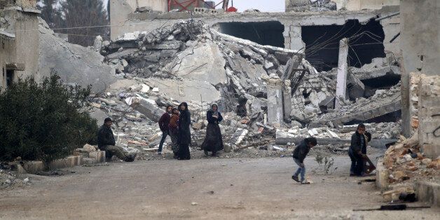 People stand near near rubble of damaged buildings in al-Rai town, northern Aleppo countryside, Syria December 25, 2016. REUTERS/Khalil Ashawi