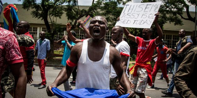 A Congolese protester holds a book of the DRC's constitution in defiance against the President of the Democratic Republic of the Congo, Joseph Kabila, at a protest demanding him to step down on December 20, 2016 in Pretoria.The United Nations voiced alarm over a wave of arrests in the Democratic Republic of Congo, where tensions were running high after President Joseph Kabila's term in office expired. Tuesday marked the end of the second and constitutionally-mandated final term for the 45-year-old, who inherited the presidency after the 2001 assassination of his father. But he is now refusing to leave the job that he began without much fanfare. / AFP / John Wessels (Photo credit should read JOHN WESSELS/AFP/Getty Images)