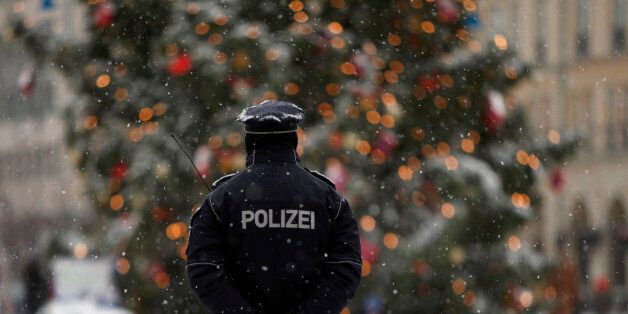 A police officer keeps watch near a Christmas tree during a snowy day in central Berlin, December 14, 2010. REUTERS/Thomas Peter (GERMANY - Tags: POLITICS ENVIRONMENT)