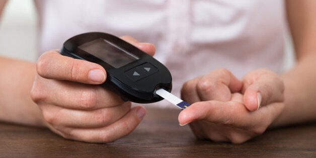 Close-up Of Person Hands Holding Glucometer At Desk