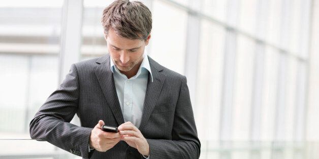 Businesswoman text messaging on a mobile phone in an office