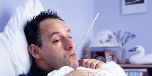 Man lying in bed, with thermometer in mouth, close-up (Enhancement)