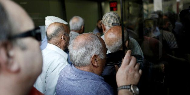 Pensioners squeeze through the entrance to a National Bank of Greece SA bank branch shortly after opening in Thessaloniki, Greece, on Monday, July 20, 2015. German Chancellor Angela Merkel held out the prospect of limited debt relief as crisis-ravaged Greece prepares to reopen its banks three weeks after they were shut. Photographer: Konstantinos Tsakalidis/Bloomberg via Getty Images