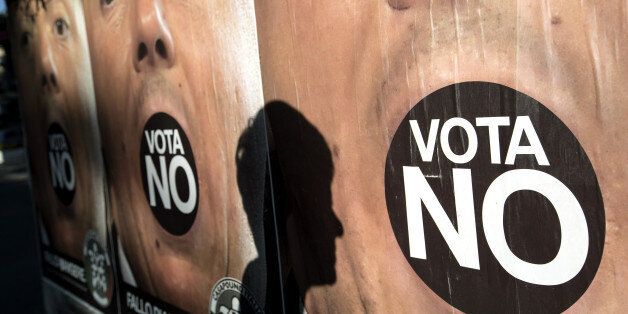 A pedestrian's shadow is cast on an advertising board displaying posters for the 'No' campaign ahead of the referendum on constitutional reform, in Rome, Italy, on Saturday, Dec. 3, 2016. On Dec. 4, Italians will vote on constitutional changes proposed by Prime Minister Matteo Renzi to limit the power of the Senate, the upper house of parliament. Photographer: Alessia Pierdomenico/Bloomberg via Getty Images