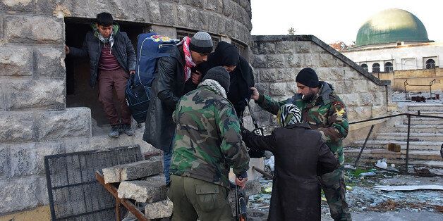 Syrian residents fleeing the violence in the eastern rebel-held parts of Aleppo are helped by pro-government forces as they evacuate from their neighbourhoods through the Bab al-Hadid district after it was seized by the regime, on December 7, 2016.In the face of a blistering assault by forces loyal to President Bashar al-Assad, the rebels were reported to have retreated from all of Aleppo's Old City, the latest in a string of territorial losses. / AFP / GEORGE OURFALIAN (Photo credit should read GEORGE OURFALIAN/AFP/Getty Images)