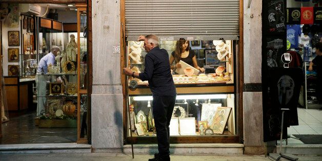 A shopkeeper closes the metal shutters outside his antique souvenir store in preparation for closing time in the Plaka tourist district of Athens, Greece, on Thursday, July 16, 2015. Germany's Parliament is set to ratify bridge financing and the start of talks for a three-year rescue plan. Photographer: Matthew Lloyd/Bloomberg via Getty Images