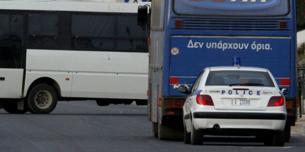 A police car is seen behind a hijacked bus on a street some 30 kilometres north of Athens December 15, 2004. Greek police forces surrounded the bus after two armed men hijacked it early Wednesday morning with 26 passengers on board on its way from northern Athens suburbs to the Greek capital. REUTERS/Yiorgos Karahalis YK/GB