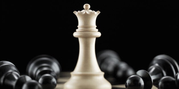 White queen chess piece surrounded by fallen black pawn chess pieces