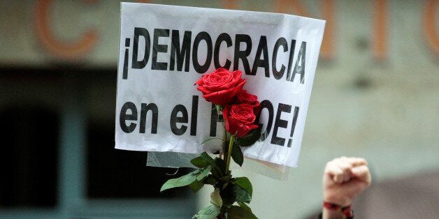 Supporters of Spain's Socialist party (PSOE) hold red roses and a poster reading