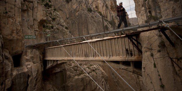 A man crosses a footbridge during a visit to the foot-path 'El Caminito del Rey' (King's little path) a narrow walkway hanging and carved on the steep walls of a defile in Ardales near Malaga on March 15, 2015. The one meter wide and 7.7 km long path, hanging from Ardales' defile at 100 meter high, was closed in the mid 90's after several hikers resulted dead when walking it. Once restored it will be reopened to the public on March 28, 2015. AFP PHOTO/ JORGE GUERRERO (Photo credit should read Jorge Guerrero/AFP/Getty Images)
