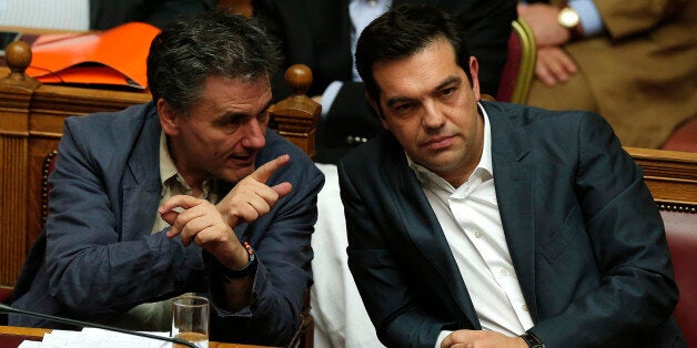 Greek Prime Minister Alexis Tsipras (R) sits next to Finance Minister Euclid Tsakalotos (L) as he attends a parliamentary session in Athens, Greece July 15, 2015. Prime Minister Alexis Tsipras battled to win lawmakers' approval on Wednesday for a bailout deal to keep Greece in the euro, while the country's creditors, pressed by the IMF to provide massive debt relief, struggled to agree a financial lifeline. REUTERS/Alkis Konstantinidis