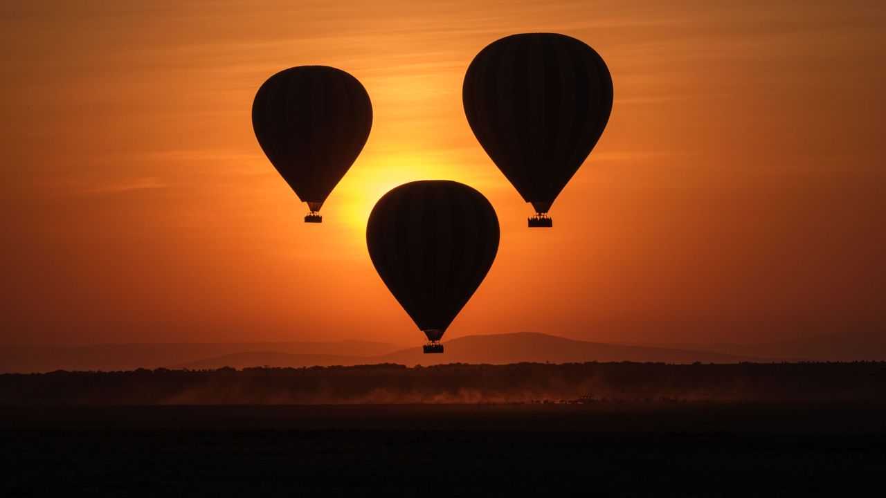 TOPSHOT - Hot-air balloons fly up with tourists at sunrise in the Masai Mara game reserve in Kenya on September 20, 2019. (Photo by Yasuyoshi CHIBA / AFP) (Photo credit should read YASUYOSHI CHIBA/AFP/Getty Images)