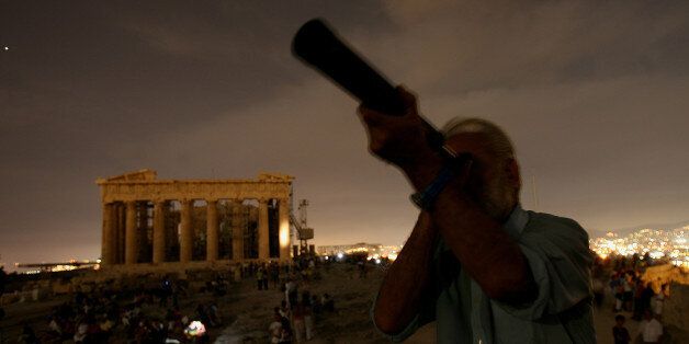 A Greek man looks through his telescope at the full moon as at the backround is seen the ancient temple of Parthenon at Acropolis hill, in Athens on Wednesday, Aug. 9, 2006. Many archaeological sites in Greece were open for the public Wednesday night for the full moon. (AP Photo/Petros Giannakouris)