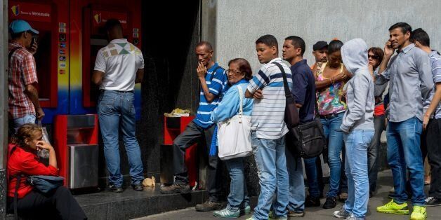 People queue to withdraw money from an automated teller machine (ATM) in Caracas on December 1, 2016.Venezuelan banks guaranteed their continued operation, after rumors about a close in December to adjust to an alleged issuance of bills of higher denomination. At the moment, the note of highest denomination is the one of 100 bolivars, that is just enough to buy a sweet. / AFP / Federico PARRA (Photo credit should read FEDERICO PARRA/AFP/Getty Images)