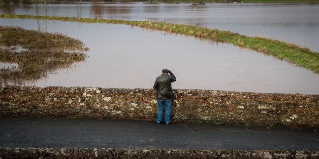 EXETER, ENGLAND - NOVEMBER 22: A man looks at flood water in fields surrounding the village of Clyst St George on November 22, 2016 near Exeter, England. In the wake of Storm Angus torrential rain brought flooding and power cuts to thousands of homes across Britain with emergency services working through the night to help victims of the floods. (Photo by Matt Cardy/Getty Images)