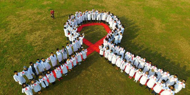 YANGZHOU, CHINA - DECEMBER 01: Aerial view of college students crowding together to form a shape of a red ribbon to raise awareness for the AIDS pandemic at Chemistry and Chemical Engineering college of Yangzhou University on December 1, 2016 in Yangzhou, Jiangsu Province of China. About 100 college students of Yangzhou University hand out red ribbons and wear masks with red ribbons to show affection for HIV-infected people in the World AIDS Day 2016. (Photo by VCG/VCG via Getty Images)