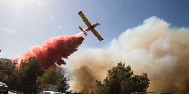 An Israeli firefighter plane helps extinguish a bushfire in the northern Israeli port city of Haifa on November 24, 2016.Hundreds of Israelis fled their homes on the outskirts of the country's third city Haifa with others trapped inside as firefighters struggled to control raging bushfires, officials said. / AFP / Jack GUEZ (Photo credit should read JACK GUEZ/AFP/Getty Images)