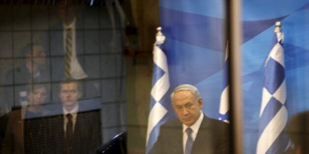 A reflection of Israeli Prime Minister Benjamin Netanyahu (C) is seen as he delivers a joint statement with his Greek counterpart Alexis Tsipras in Jerusalem, November 25, 2015. REUTERS/Ronen Zvulun