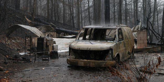 GATLINBURG, TN - NOVEMBER 30: The remains of a van and home smolder in the wake of a wildfire November 30, 2016 in Gatlinburg, Tennessee. Thousands of people have been evacuated from the area and over 100 houses and businesses were damaged or destroyed. Drought conditions and high winds helped the fire spread through the foothills of the Great Smoky Mountains. (Photo by Brian Blanco/Getty Images)