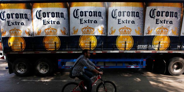 A man cycles past a truck of Corona beer produced by Group Modelo in Mexico City July 16, 2013. After years of complaints from SABMiller, the world's second-largest brewer but barely a blip on the Mexican radar, global leader Anheuser-Busch InBev and third-ranking Heineken have agreed with regulators to curb exclusivity deals with Mexican retailers that have secured them a combined 99 percent of the market through their local units. The incumbents could concentrate exclusive agreements in the re