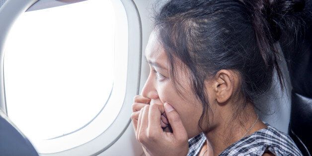 frightened woman looking out an airplane window