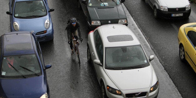 Cars caught in a traffic jam as a cyclist passes among them during a 24-hour strike held by metro, tram and urban railway unions in Athens, Friday, Jan. 18, 2013. Athenians use their cars as workers at Athens metro, tram and urban railway system have walked off the job, striking to protest salary cuts that are part of harsh austerity measures the country is taking to get its hands on bailout cash it needs to avoid bankruptcy. (AP Photo/Thanassis Stavrakis)