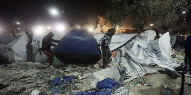 Migrants move their tent following an explosion and fire at a migrant camp on the island of Lesbos early on November 25, 2016.Angry migrants set fire to a camp on the Greek island of Lesbos after a woman and a six-year-old child died following a gas cylinder explosion, local police said. / AFP / STR (Photo credit should read STR/AFP/Getty Images)
